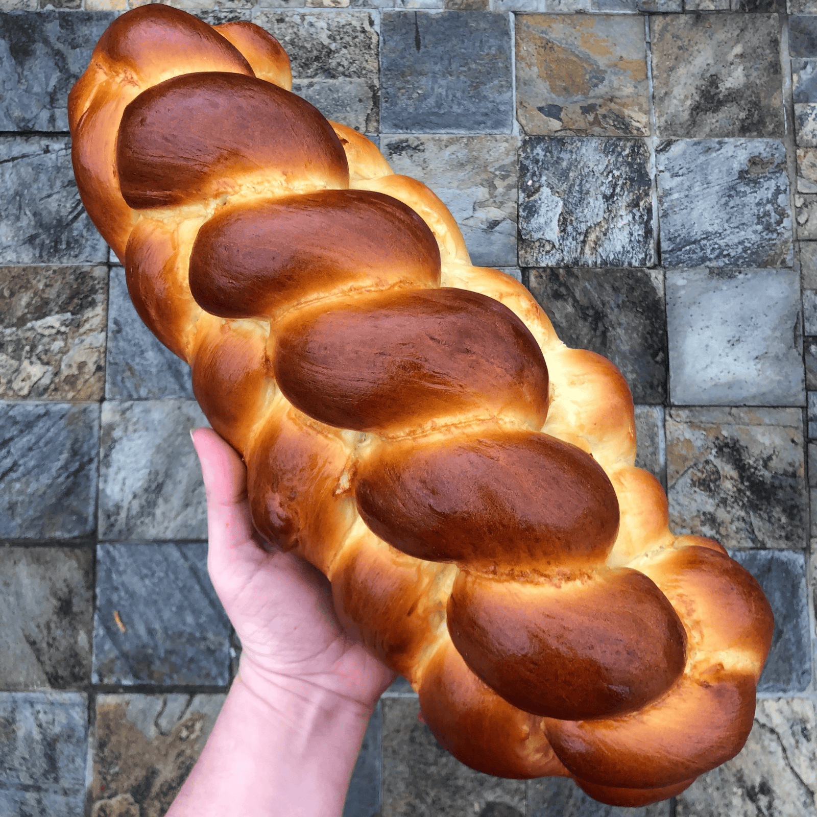 braided 5*strand loaf of Tsoureki on a slate table.