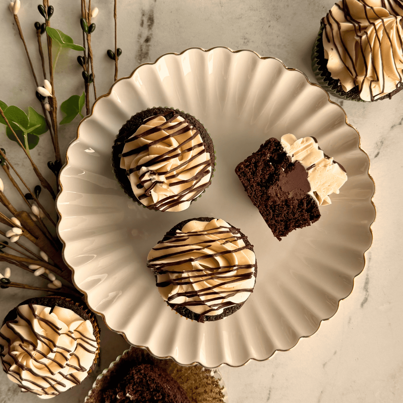 cupcakes on a plate with green decoration nearby.