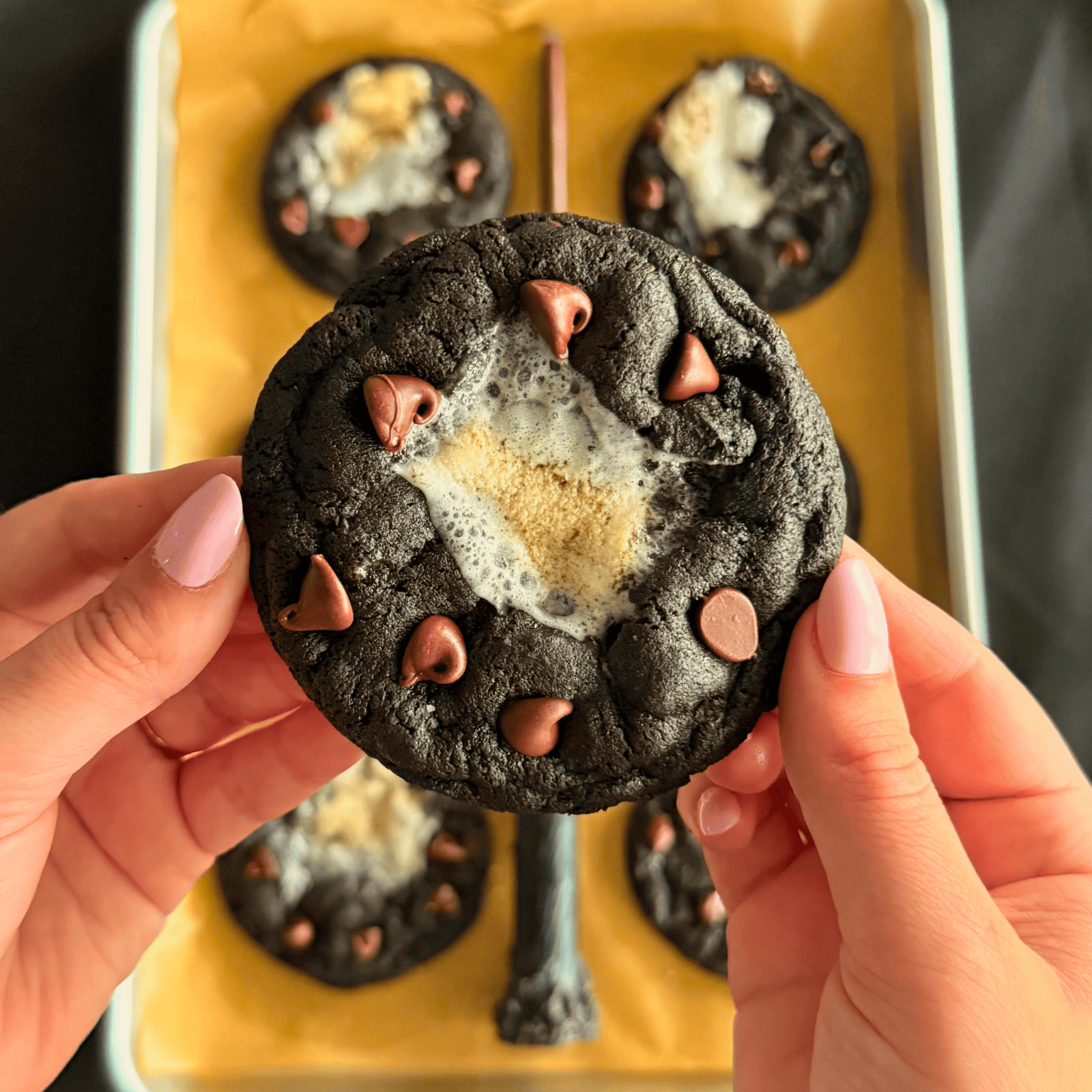 hands holding a cookie above a baking tray of dementor cookies, with a wand in the middle.